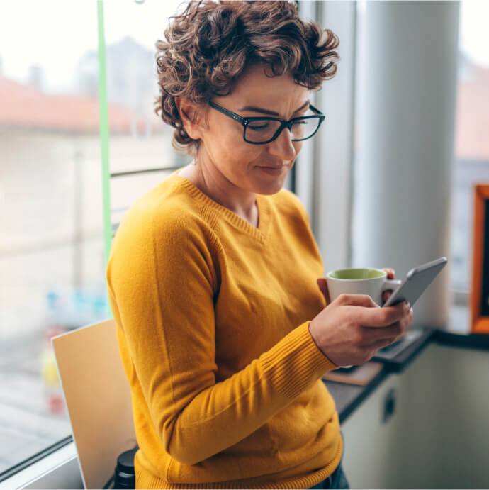 Frau mit Tasse und Mobiltelefon